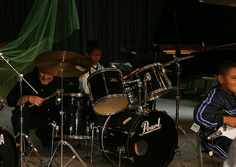Schlagzeugschüler mit Band beim Auftritt in der Musikschule